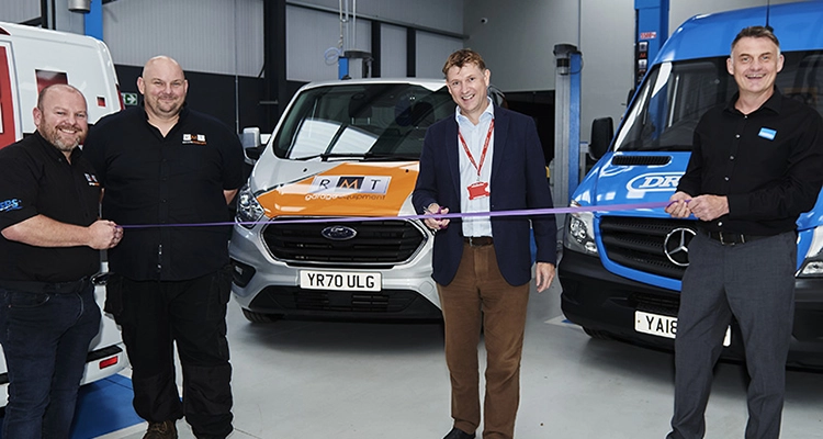 Principal cutting ribbon in front of cars